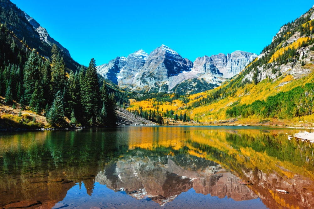 Rocky Mountain landscape with snow-covered peaks beneath a dramatic blue sky printed on a premium aluminium wall art panel.